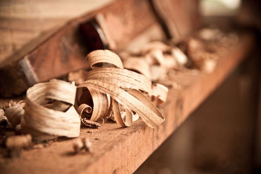 Wooden shavings and curls resting on a workbench inside a small woodworking shop.